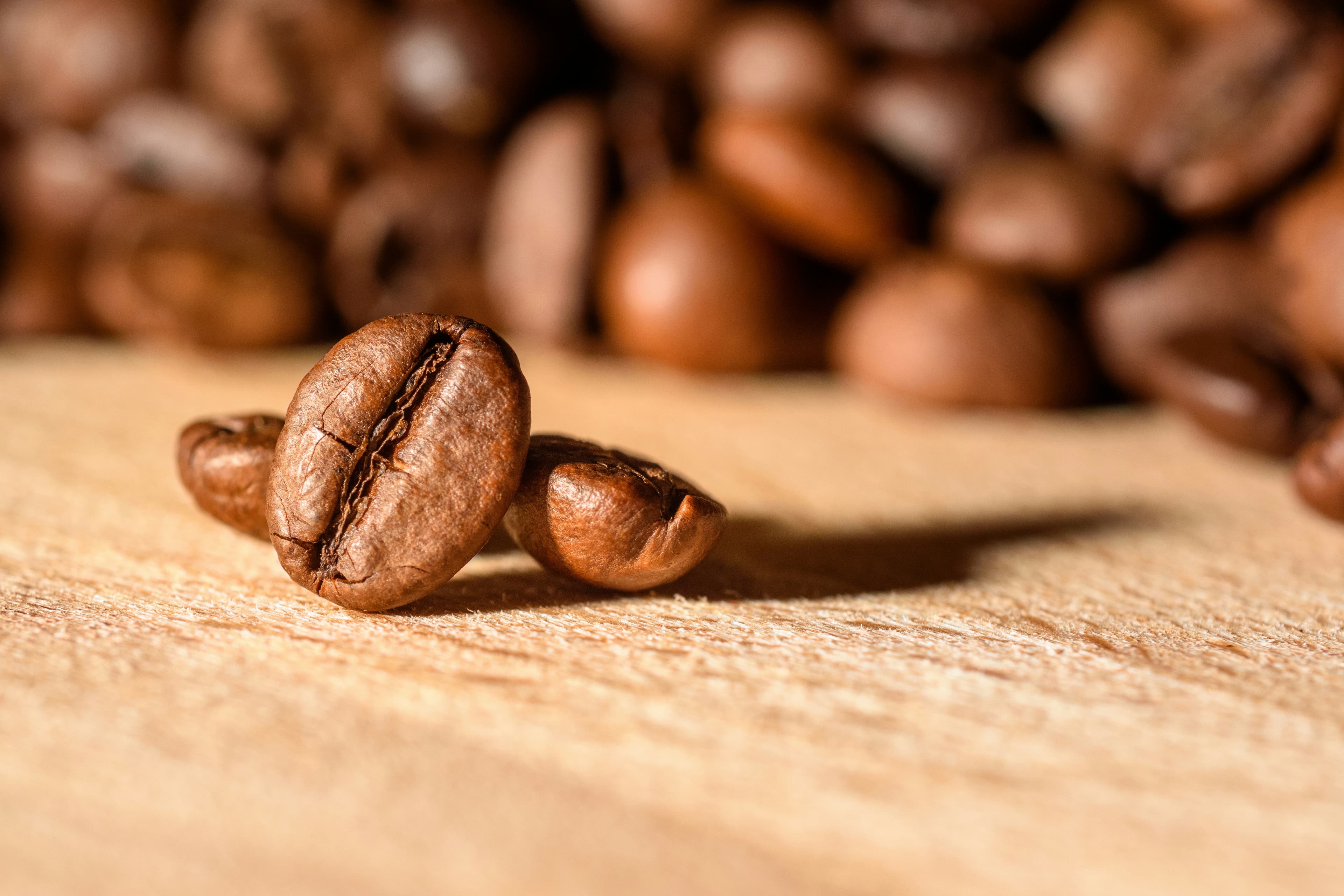 Granos de café tostado sobre una superficie de madera